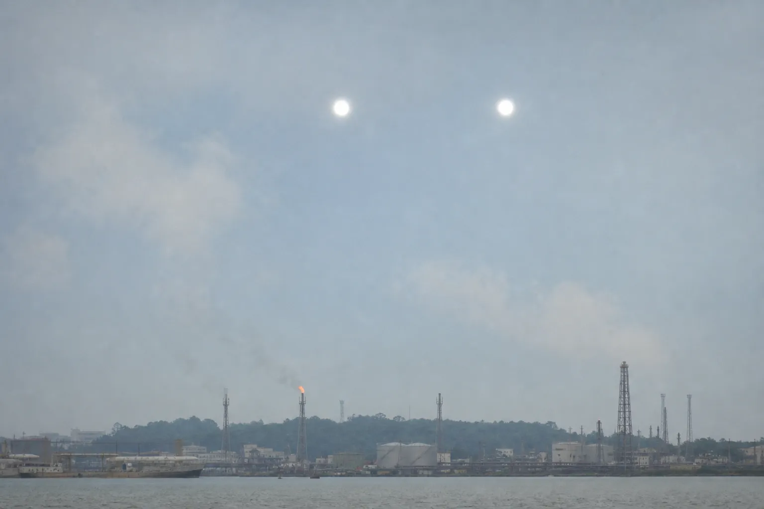 AI-rendered impression — two intensely bright spherical lights hovering stationary in formation over the coastal oil district of Lumut, Brunei, February 2011